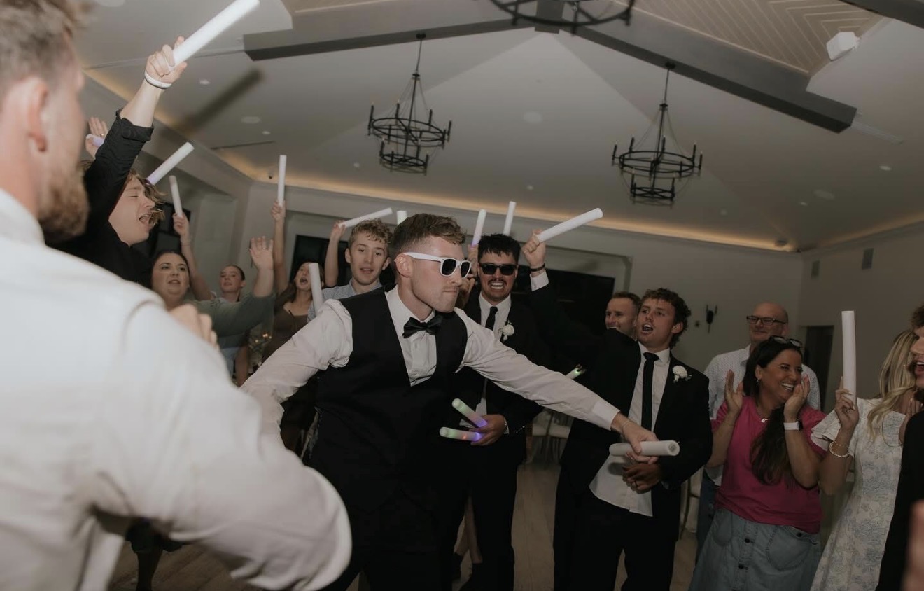 Wedding guests dancing with glowing foam sticks at the reception